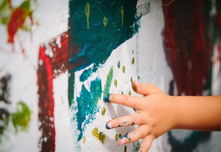 Mano di bambino che dipinge di blu con un dito