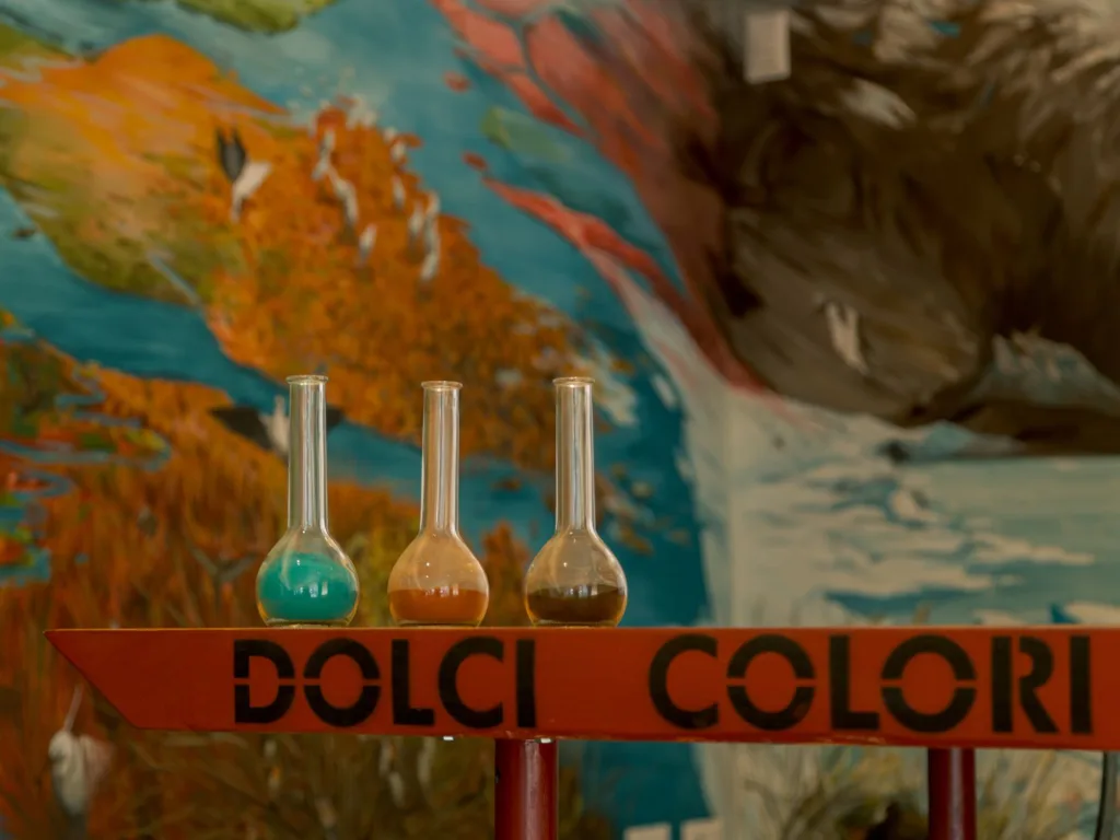 Tavolo in legno rosso con scritta Dolci Colori e sfondo colorato